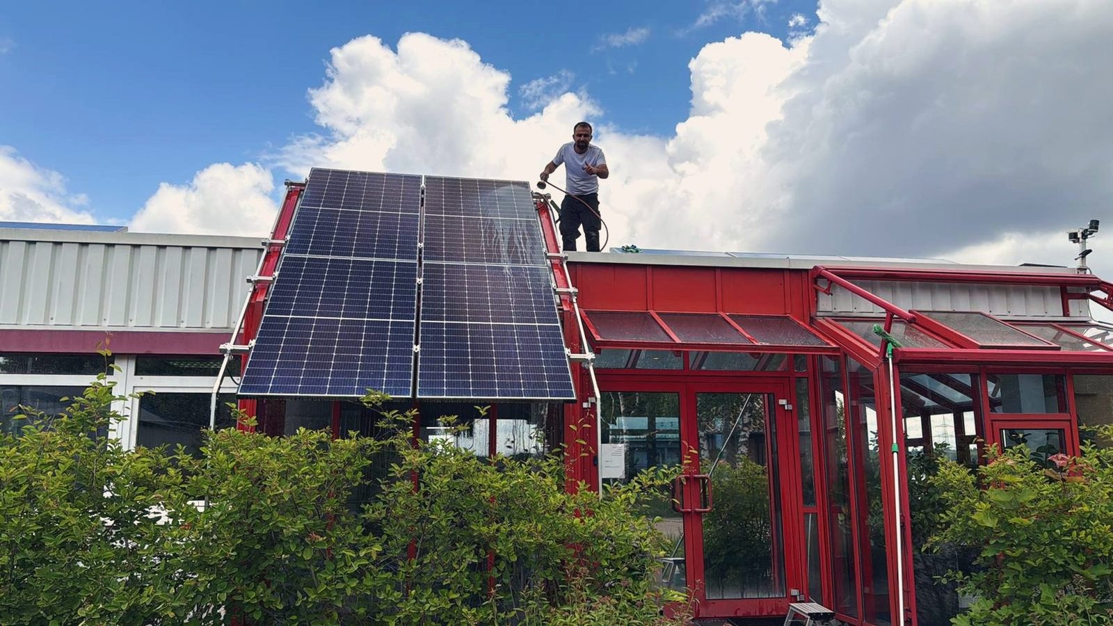acko-Mitarbeiter reinigt eine Solaranlage auf einem Flachdach