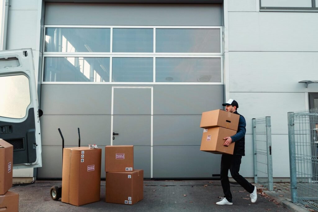 Lieferant trägt Kartons vom Transporter zu einer Halle